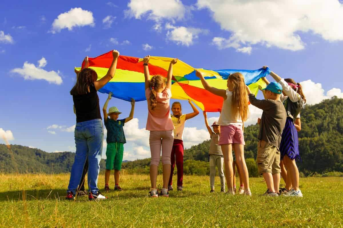 Bambini in un prato che reggono un telo colorato
