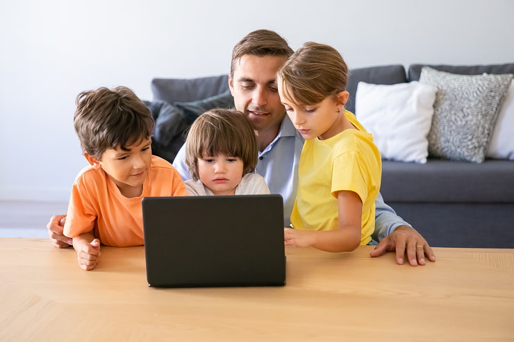 Papà che guarda il computer con i suoi bambini